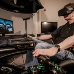 Person in a flight-simulator cockpit wearing a VR headset, gripping control levers and surrounded by screens and panels