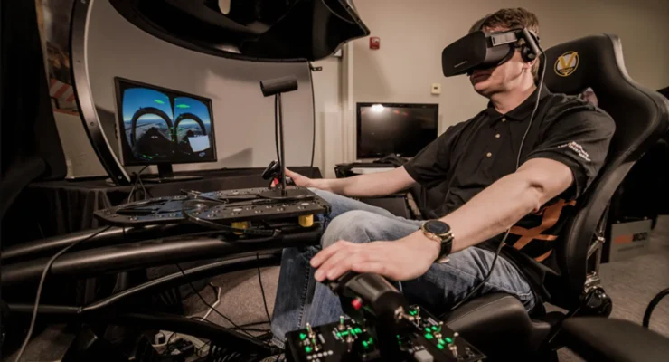 Person in a flight-simulator cockpit wearing a VR headset, gripping control levers and surrounded by screens and panels